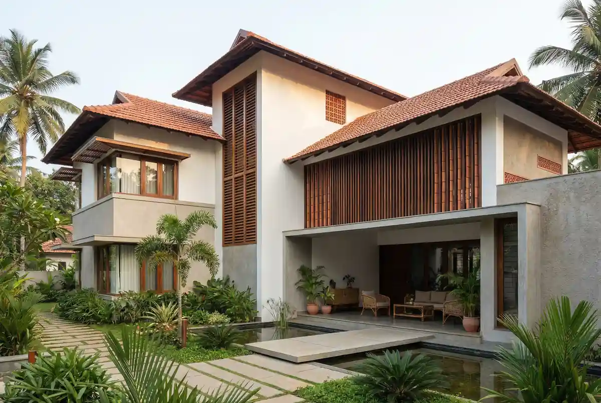 Two-storey home with deep tiled eaves, tall timber louvre screens and an open ground-floor living space beside water