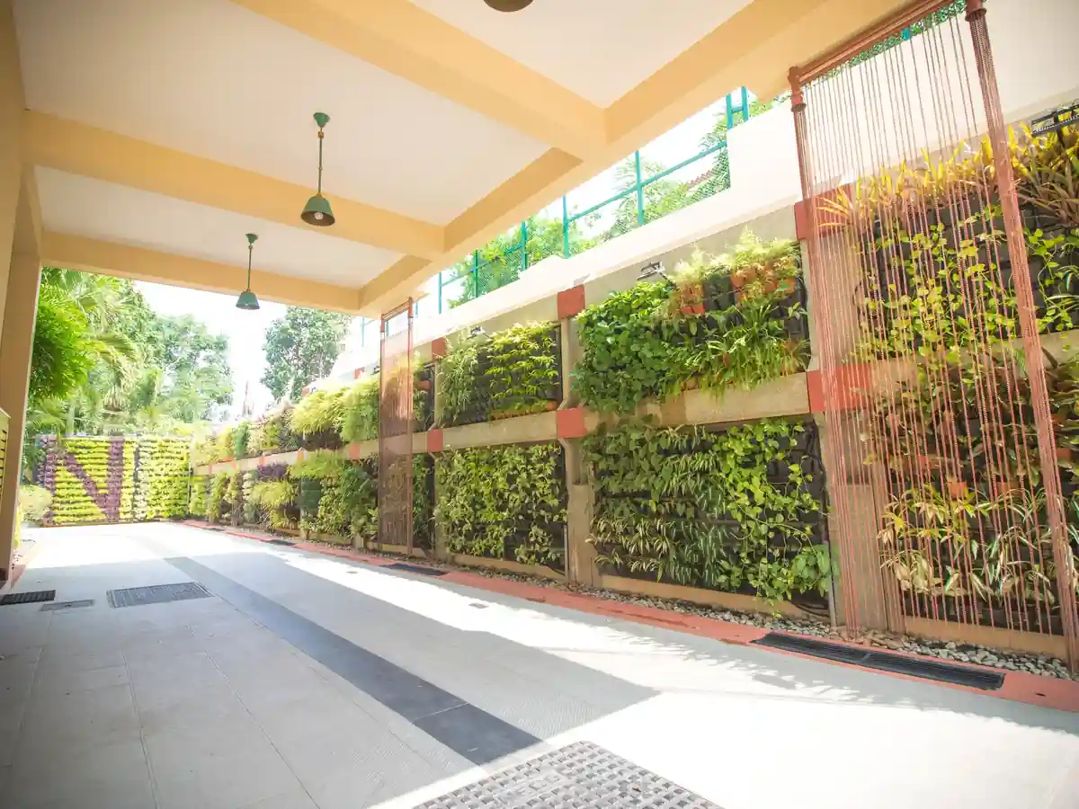 Covered side drive running along a tall planted green wall, with timber screens and the garden visible at the far end